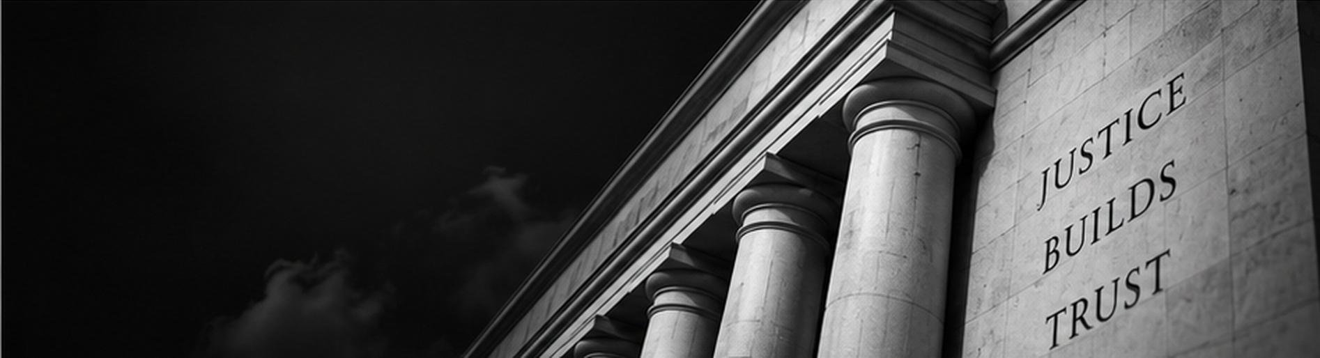 Monochrome courthouse columns engraved with the words Justice Builds Trust